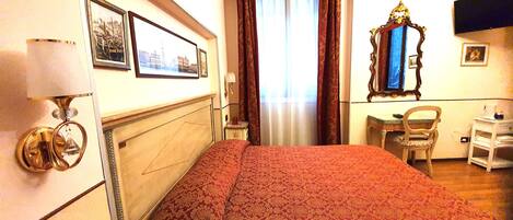 Una habitación de hotel con una cama, un escritorio, una silla, un espejo y una ventana con cortinas.