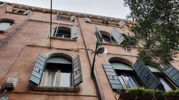 A building facade with multiple windows, some with shutters, and a sign reading "Calle de Ca Bragadín al Cristo".