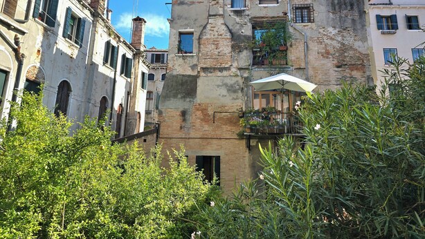 A historic building with multiple stories, featuring a mix of brick and plaster facades, and a balcony with potted plants. - Residenza degli Angeli (Venice)