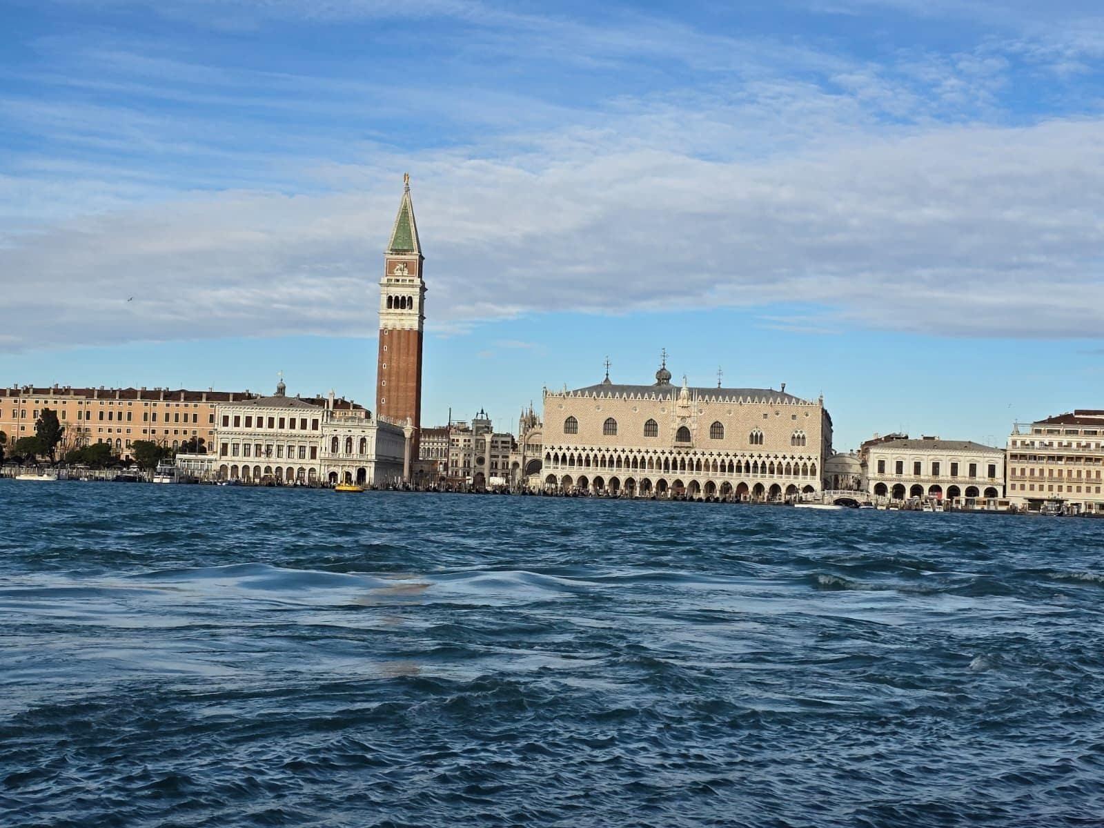 A historic building with a prominent tower and a large arched structure across a body of water.