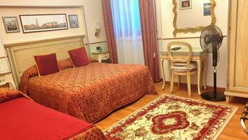 Een hotelkamer met twee bedden, een bureau, een stoel, een ventilator en een grote spiegel.