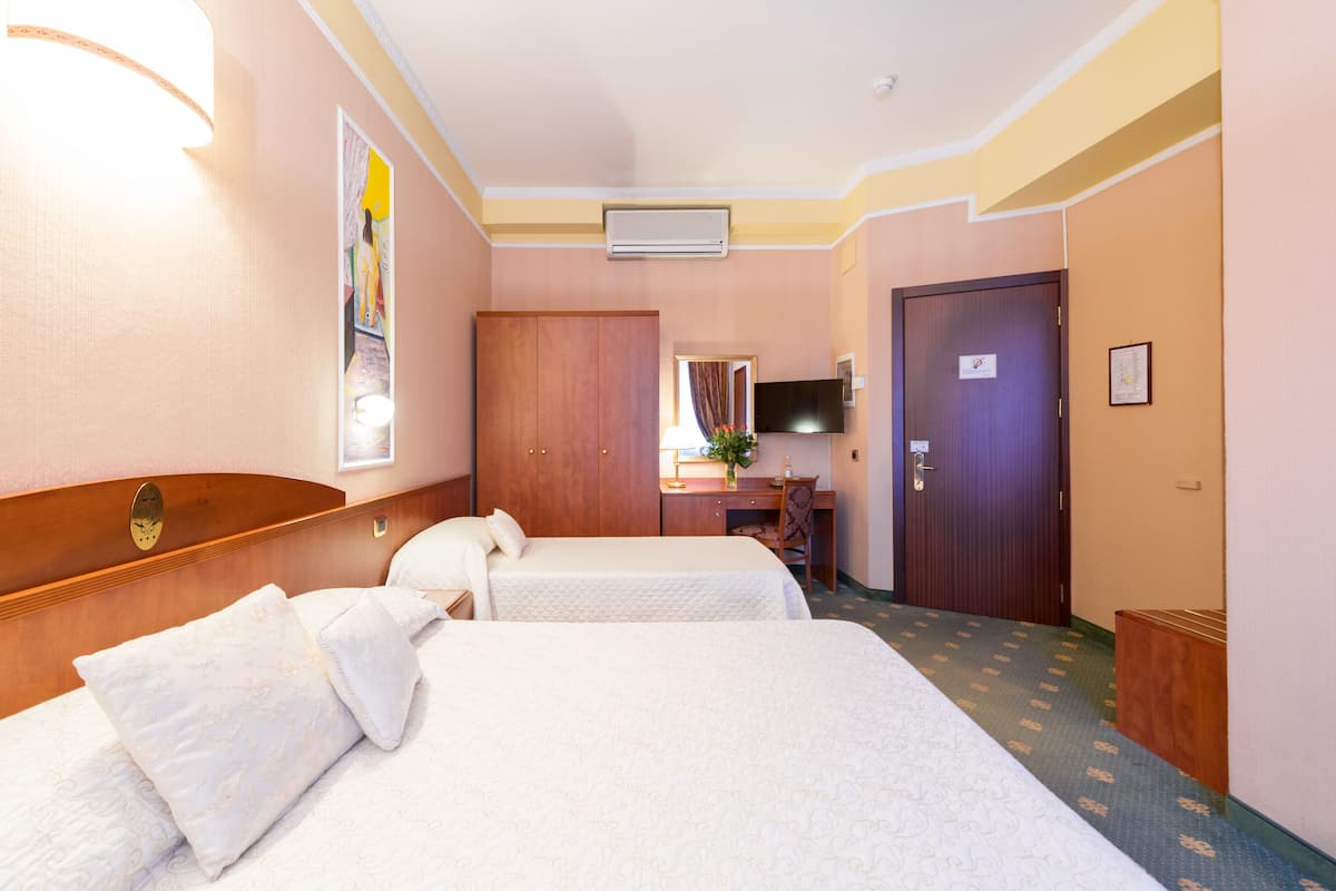 A hotel room with two beds, a desk, a TV, and a wardrobe.