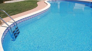 Una piscina con borde de azulejos y una escalera metálica.