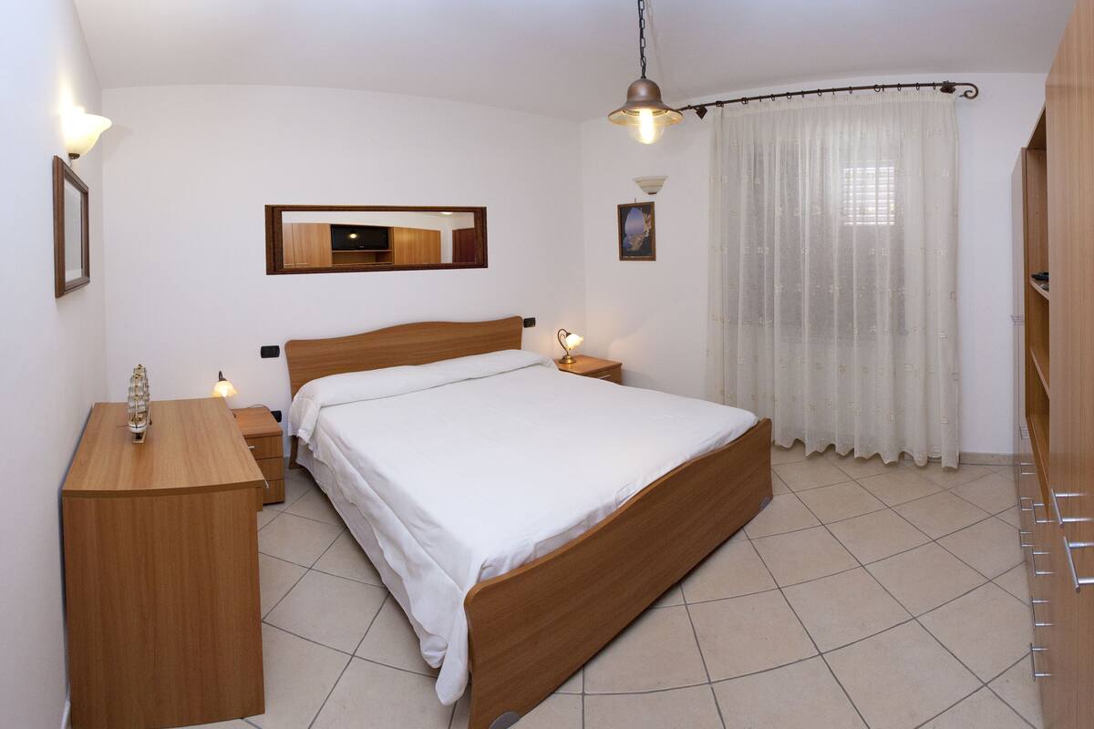 Una camera da letto con un letto in legno, comodini, una scrivania e uno specchio.