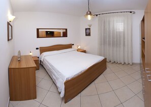 A bedroom with a wooden bed, bedside tables, a desk, and a mirror.