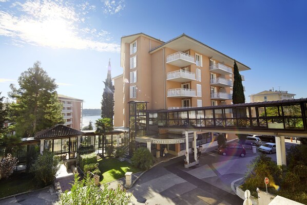 Un hôtel doté d’une entrée en verre, de places assises en plein air et offrant une vue sur la mer.