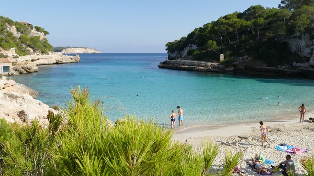 Une plage bordée d’une eau turquoise et limpide, de falaises rocheuses et d’une végétation luxuriante.