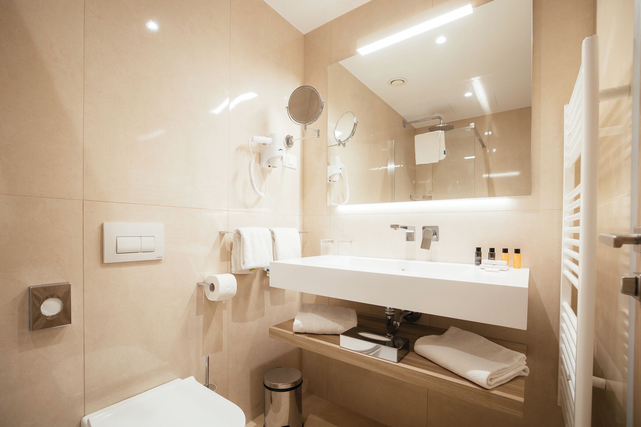 A modern bathroom with a large mirror, a sink, and a toilet.