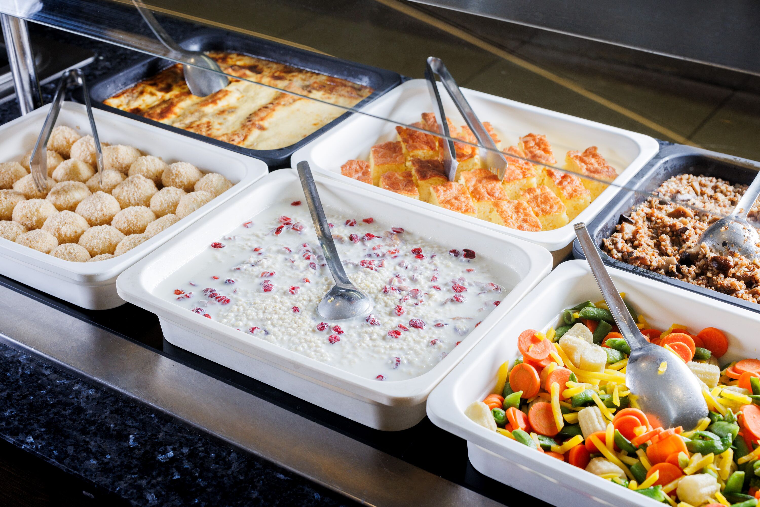 Un bufé con diversas opciones de comida, incluyendo arroz, papas y verduras.