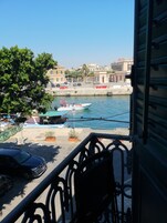 A balcony with a view of a harbor, boats, and a car parked on the street.