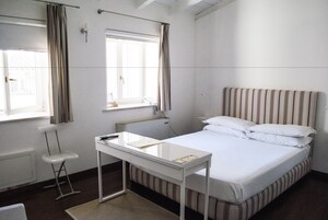 Una habitación de hotel con una cama individual, un escritorio pequeño y una silla.