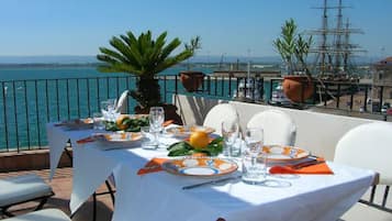 Dine al fresco with a view of the water, surrounded by lush greenery and a metal railing.