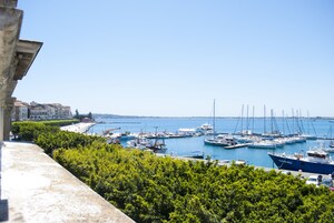 Un puerto deportivo con barcos amarrados, un cielo azul despejado y edificios al fondo.