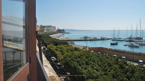 A coastal marina with boats, a clear sky, and buildings in the background. - L'Approdo delle Sirene (Syracuse)