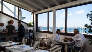 A restaurant with white furniture and large windows overlooking the sea. - L'Approdo delle Sirene (Syracuse)