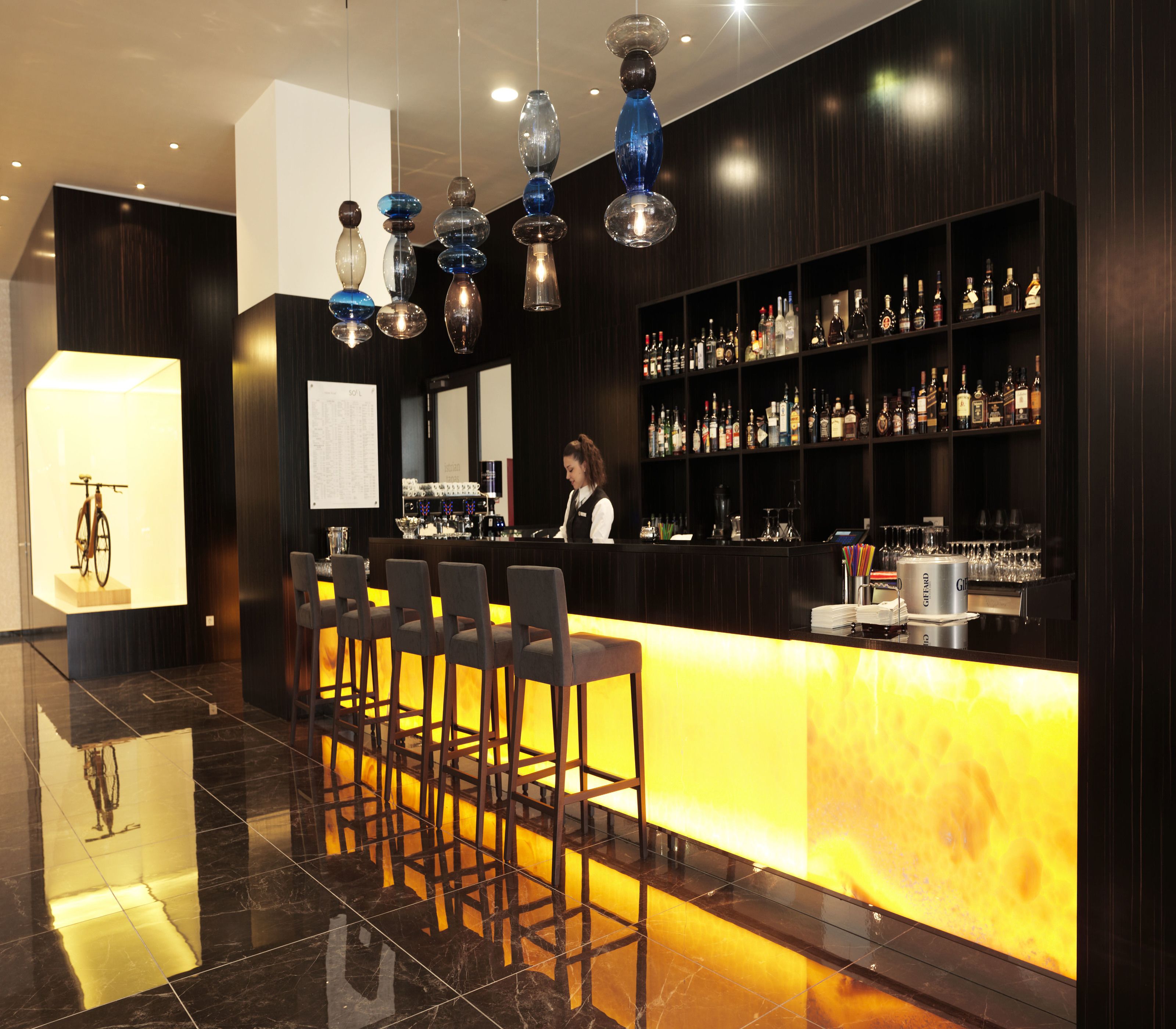 A bar area with a counter, bar stools, and a variety of bottles.