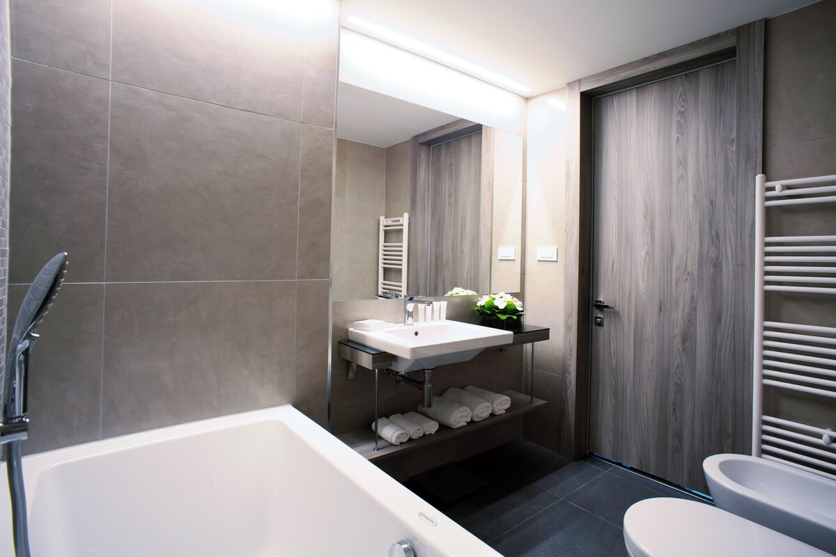 Une salle de bain moderne équipée d’une baignoire, de toilettes et d’un meuble-lavabo avec un évier et un porte-serviettes.