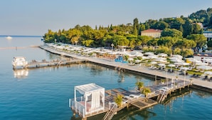 A waterfront hotel with a dock, lounge chairs, and umbrellas.