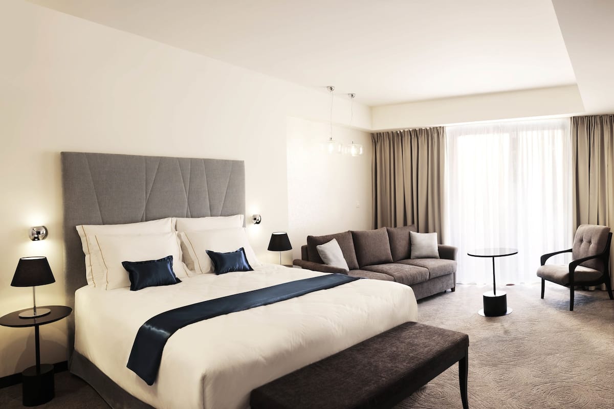 Una habitación de hotel moderna con una cama grande, un sofá, un escritorio y un televisor.