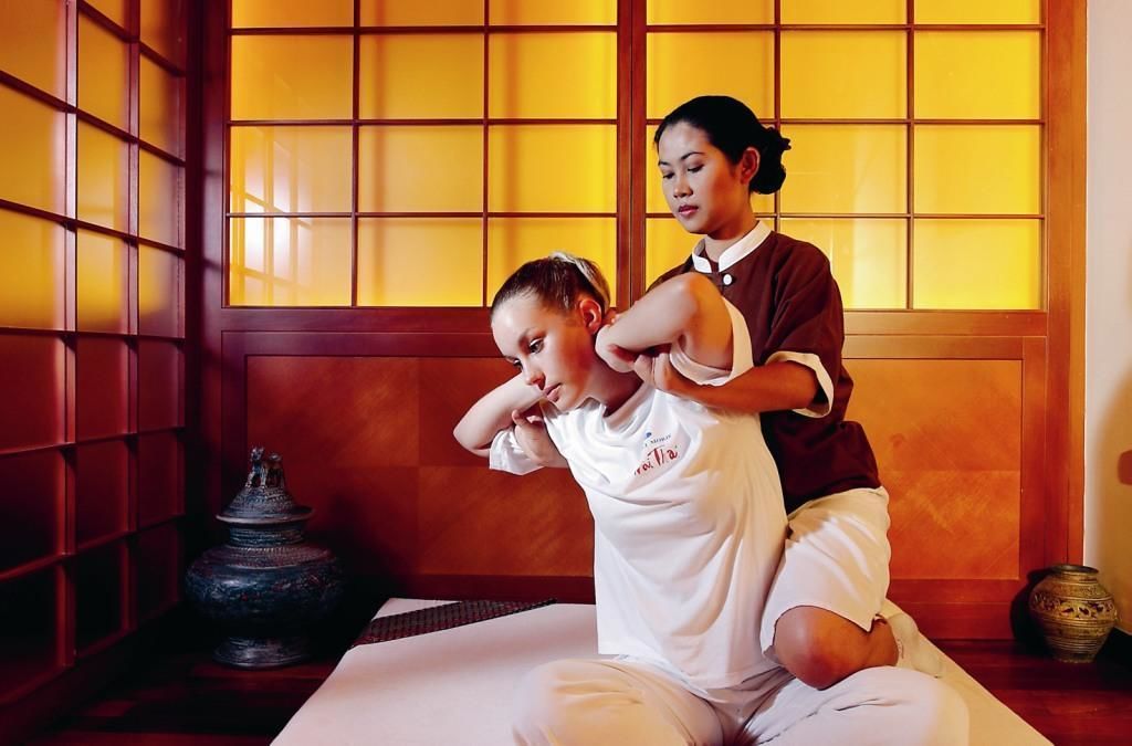 Eine Massageanwendung in einem Raum mit traditioneller Ausstattung, darunter eine Tatami-Matte und ein Shoji-Bildschirm.