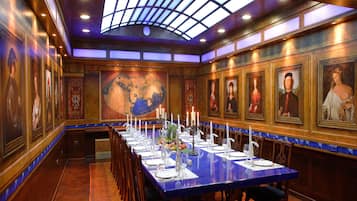 A long dining table with chairs, candles, and a world map on the wall.