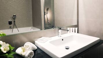 A modern bathroom with a large white sink, a glass shower enclosure, and a mirror above the sink.