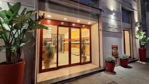 A hotel entrance with a modern design, featuring a glass door, a reception area, and potted plants. - Hotel Principe Eugenio (Rome)