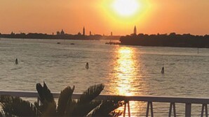A sunset over a body of water with a city skyline in the background. - Oasis Lagoon Estate (Venice)