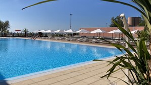 A swimming pool with lounge chairs and umbrellas, surrounded by a tiled deck. - Oasis Lagoon Estate (Venice)
