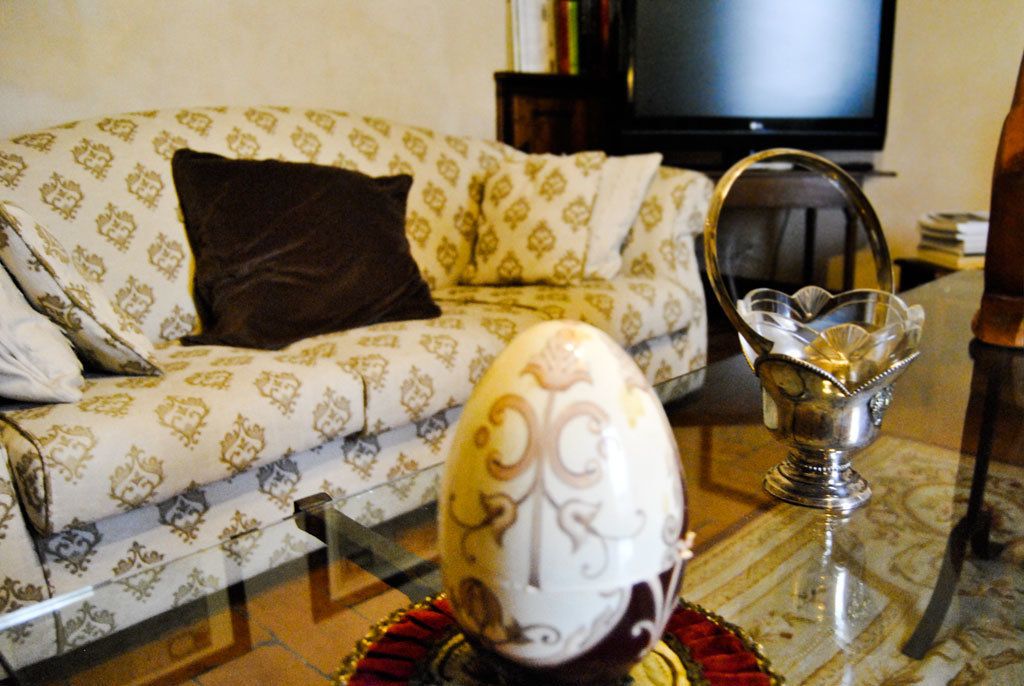 A living room with a patterned sofa, a decorative egg, and a glass bowl on a glass table.