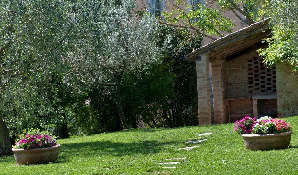 A garden with a brick structure, potted plants, and a pathway.