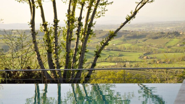 Una piscina con vista su un paesaggio verde e alberi.