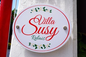A circular sign with the text "Villa Susy Relais" and decorative elements.