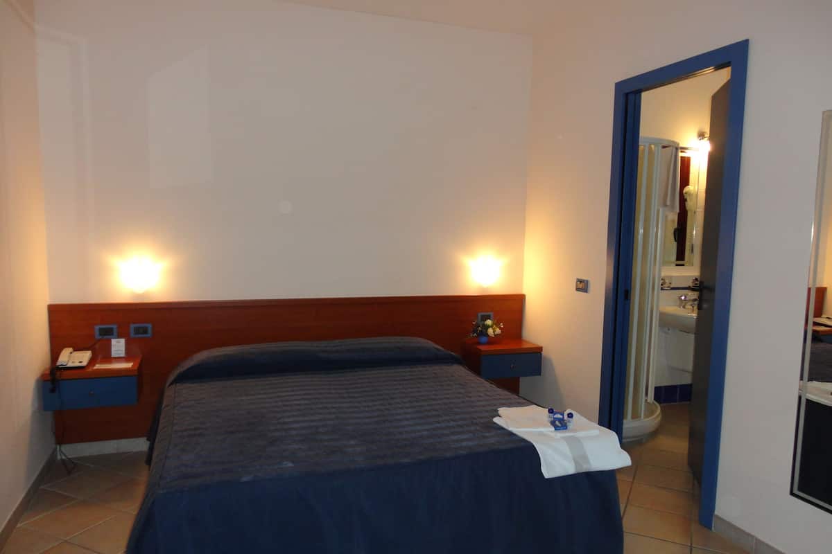 A hotel room with a bed, bedside tables, a phone, and a mirror.