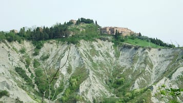 A hillside with a building on top, surrounded by trees and rocky terrain.