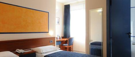 A hotel room with two beds, a desk, a chair, and a large window with curtains.