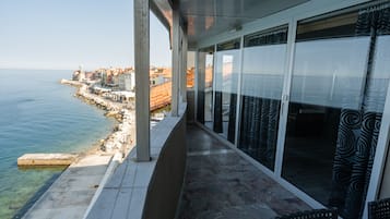 A balcony with a view of the sea, a tiled floor, and a chair.