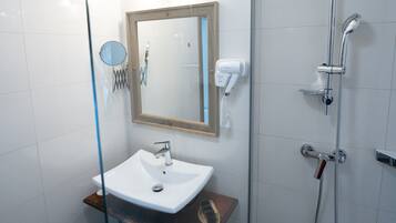 A modern bathroom with a glass shower enclosure, a white sink with a wooden countertop, and a mirror with a wooden frame.