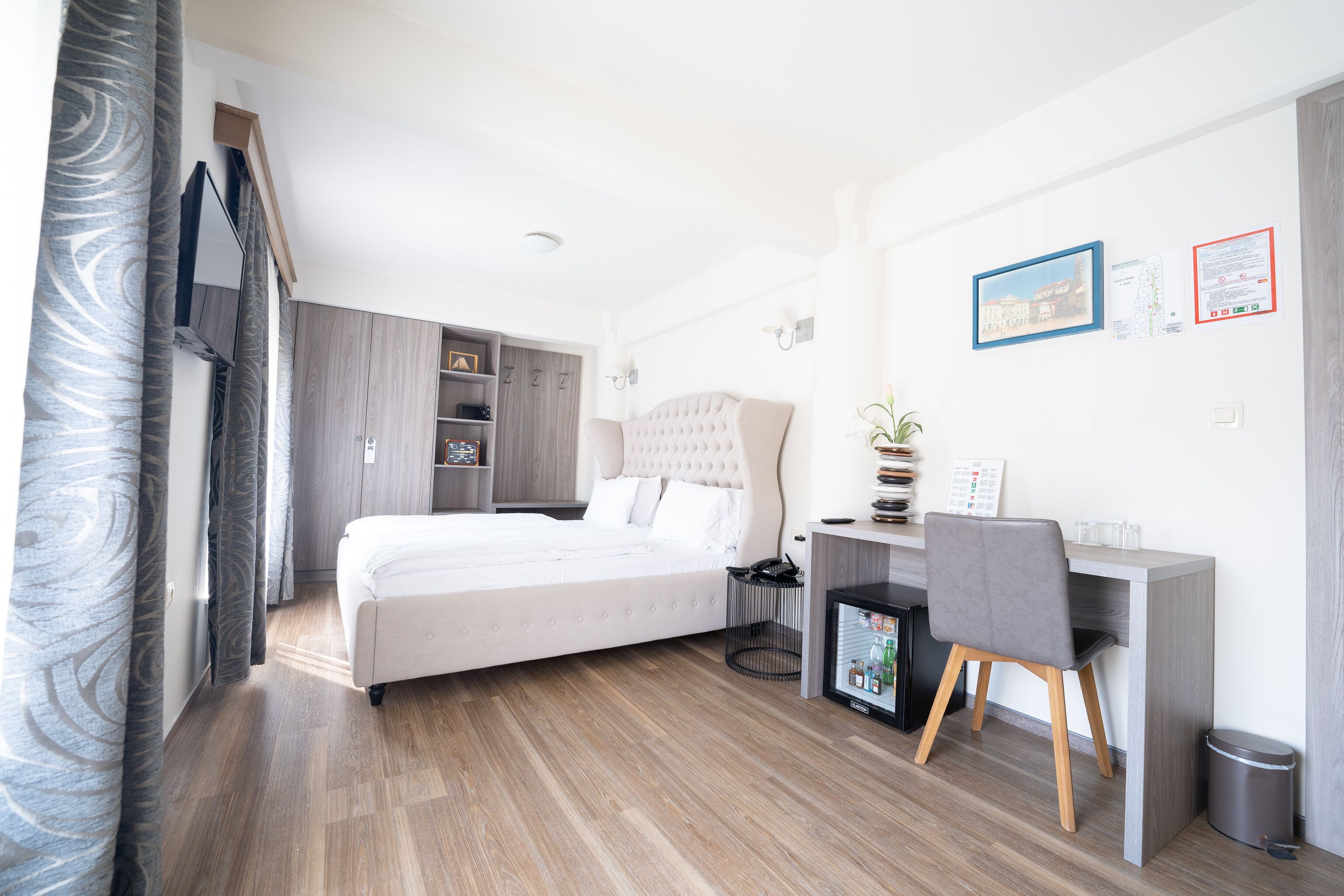 Een moderne hotelkamer met een bed, bureau, stoel en een kleine prullenbak.