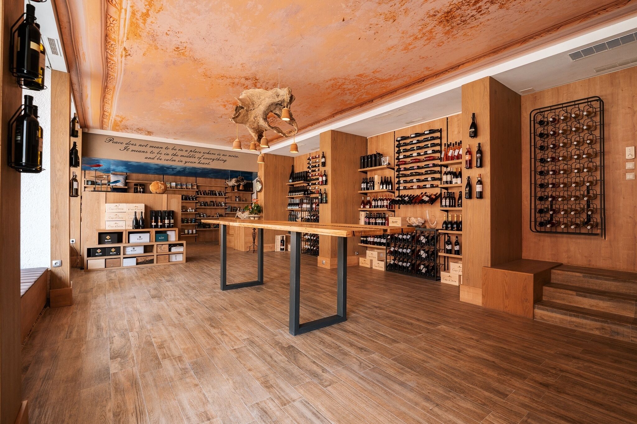 Un celler de vi amb terres de fusta, calaixos per guardar ampolles i una taula al centre.