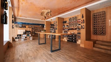 Una bodega con suelos de madera, estanterías para vino y una mesa central.