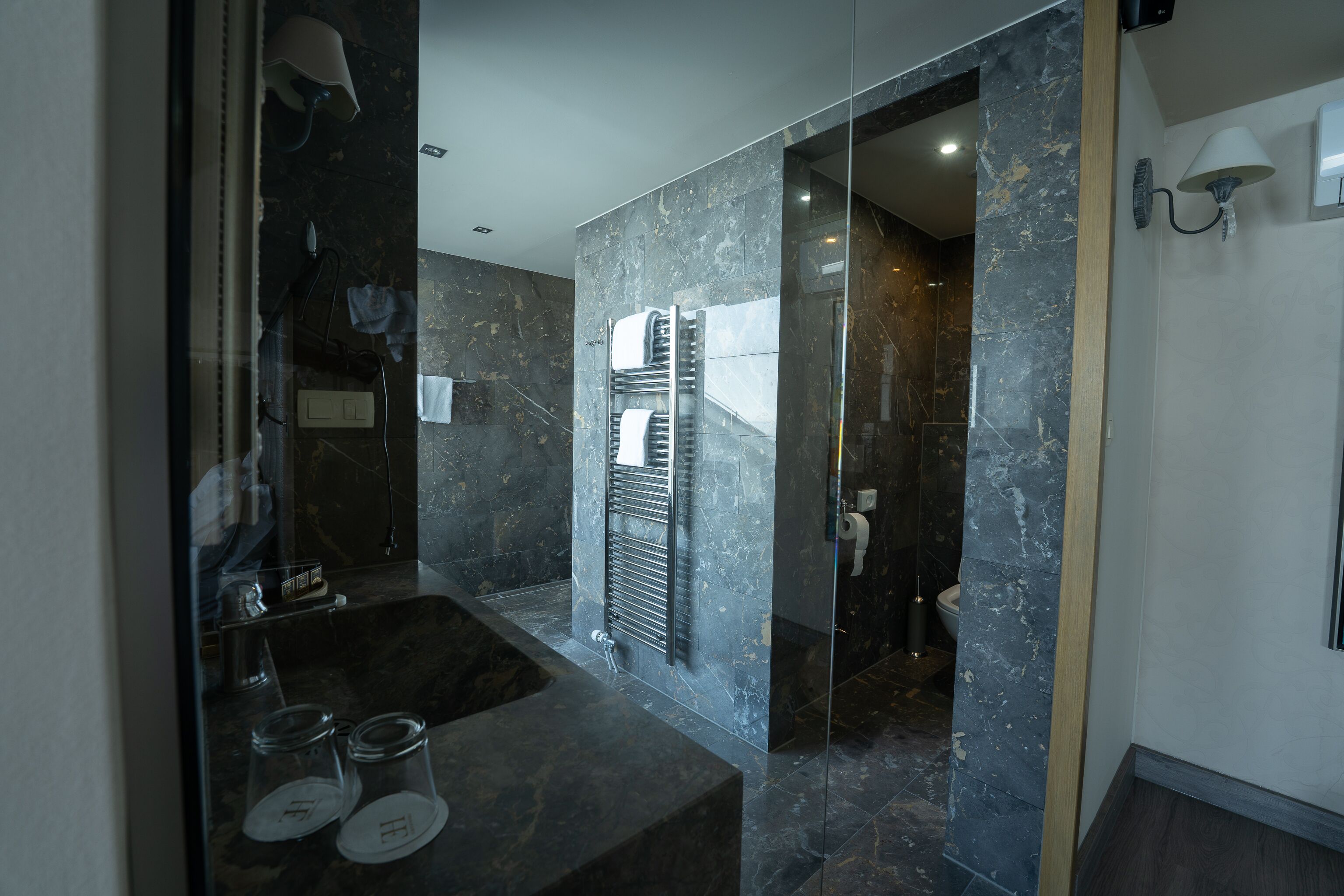 Un baño moderno con lavamanos de mármol, cabina de ducha de vidrio y puerta de cristal que da acceso a la zona de ducha.