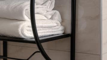Casa de banho com um porta-toalhas de metal preto exibindo toalhas brancas dobradas.