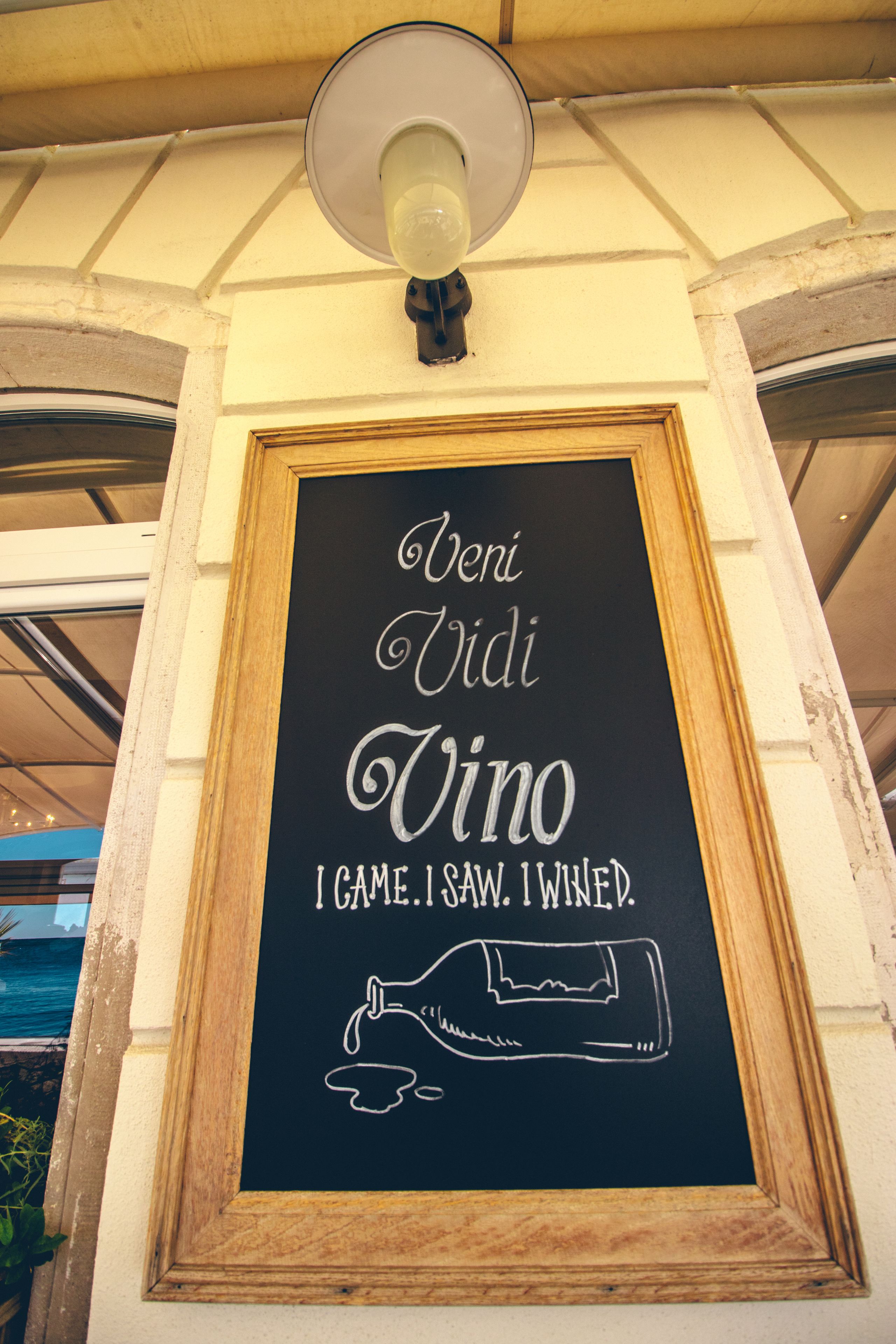 A chalkboard sign with the text "Veni Vidi Vino" and a drawing of a wine bottle.
