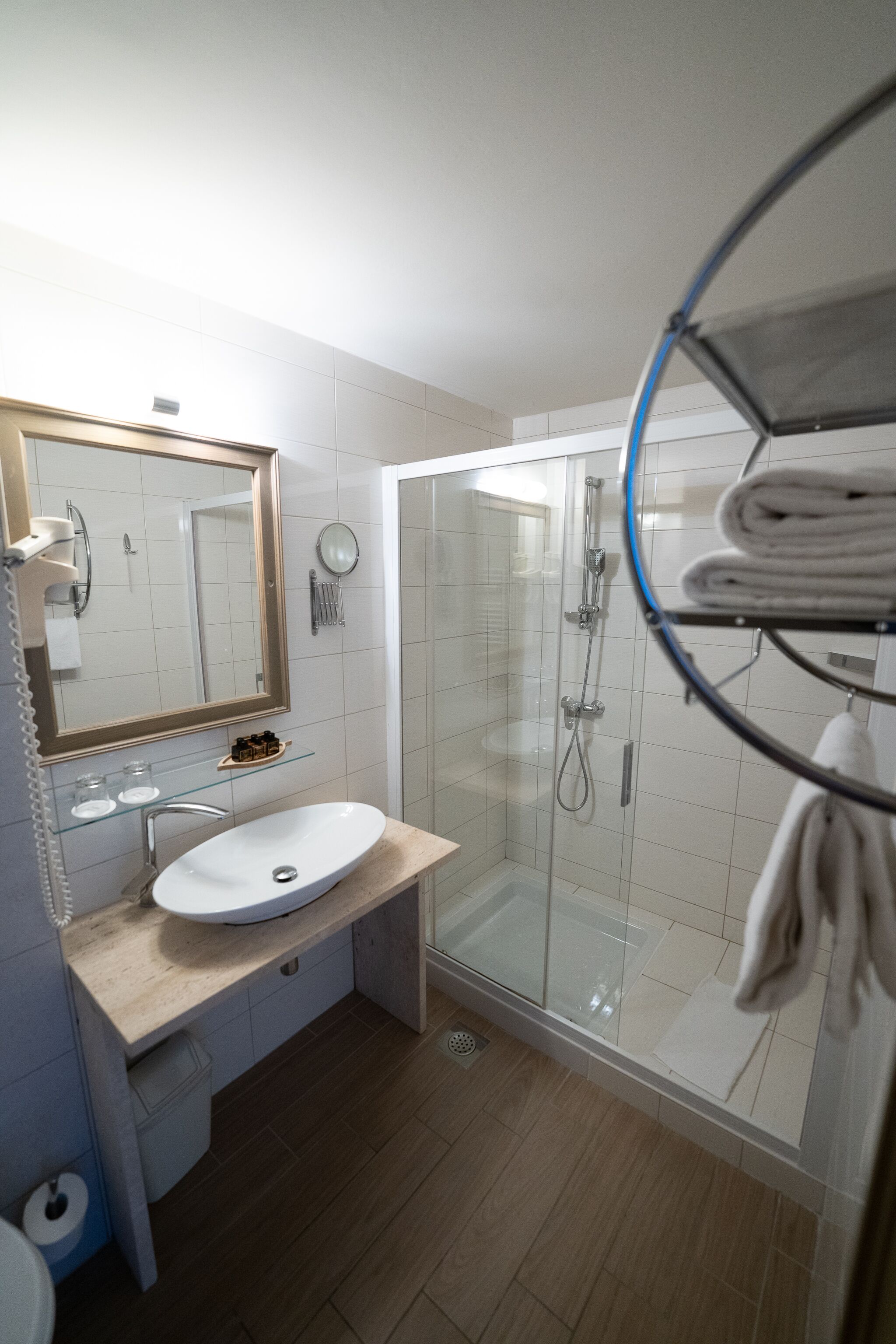 A modern bathroom with a glass-enclosed shower, a white sink, and a mirror.