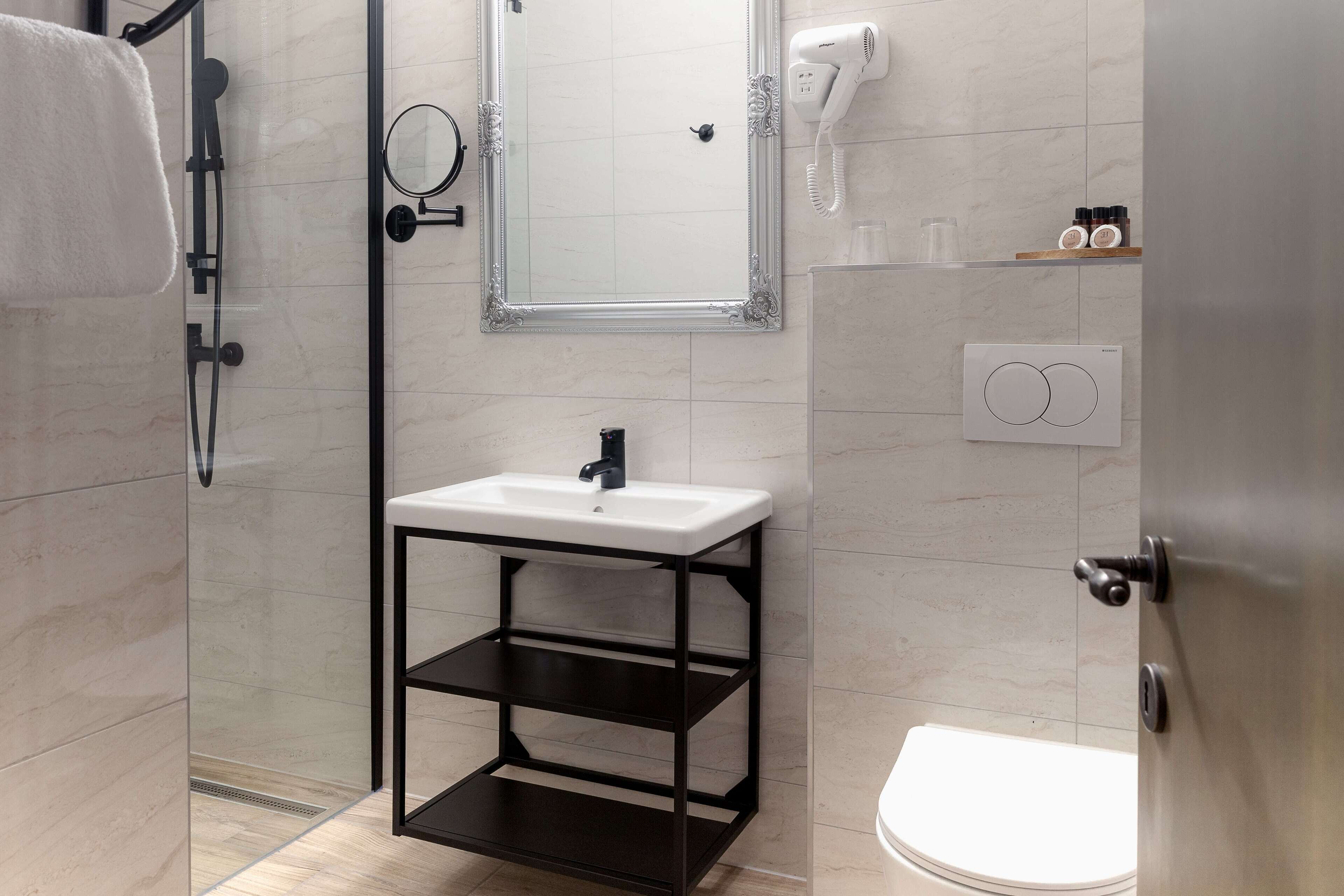 A modern bathroom with a glass-enclosed shower, a white sink with a black frame, and a toilet.