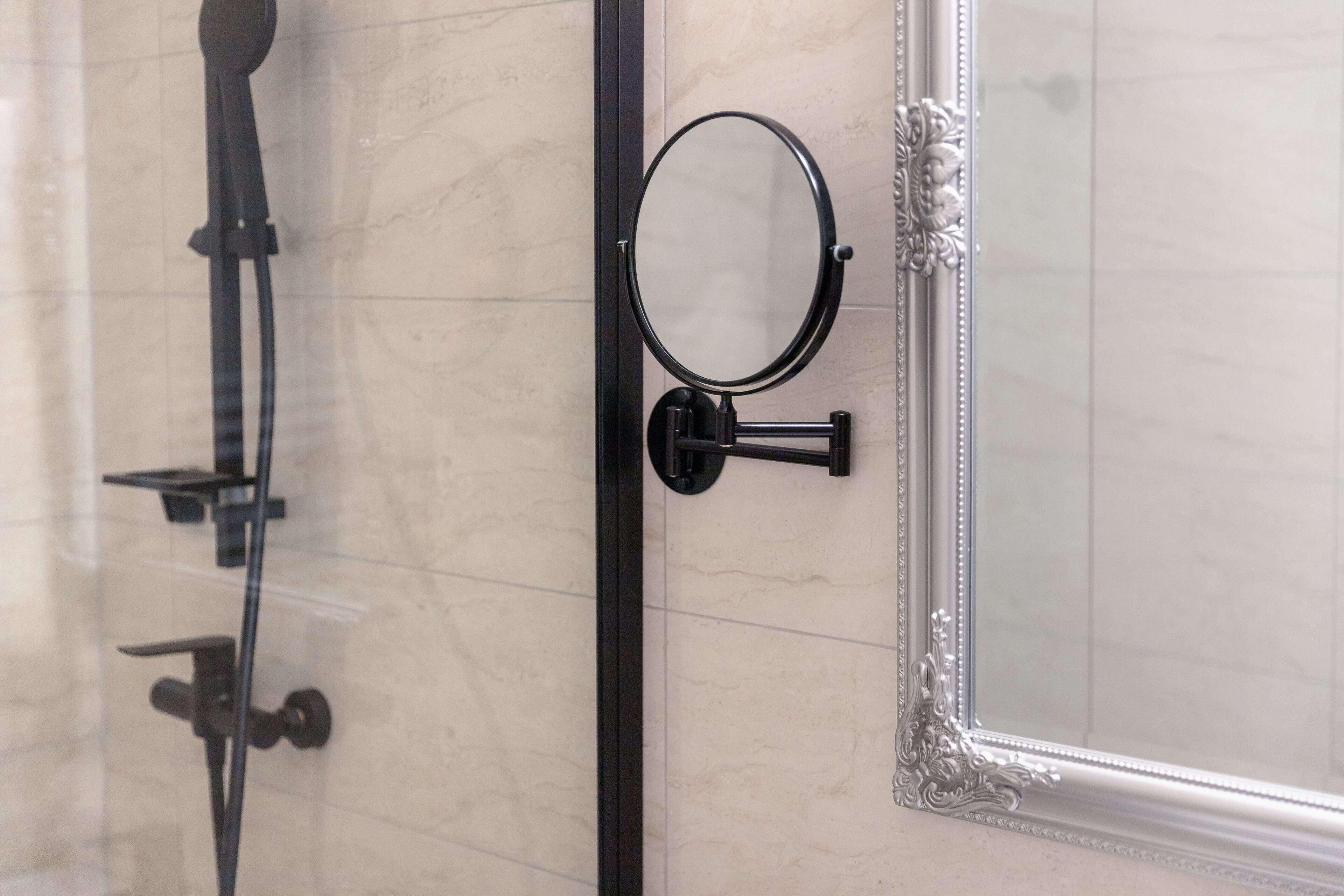A bathroom with a shower, a mirror, and a decorative frame on the wall.