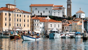 A waterfront with boats docked, historic buildings, and a prominent clock tower. - Hotel Piran (Piran)