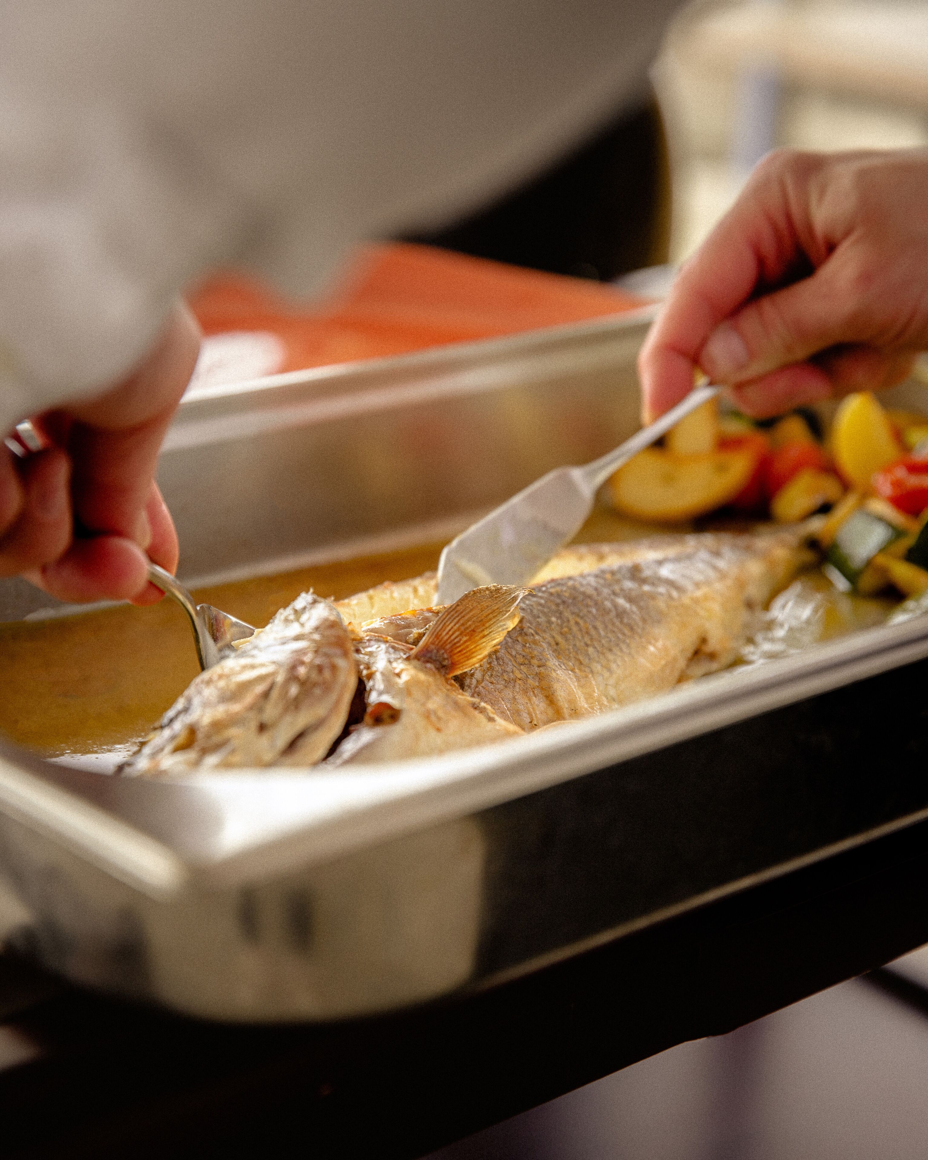 A person serving fish from a tray.