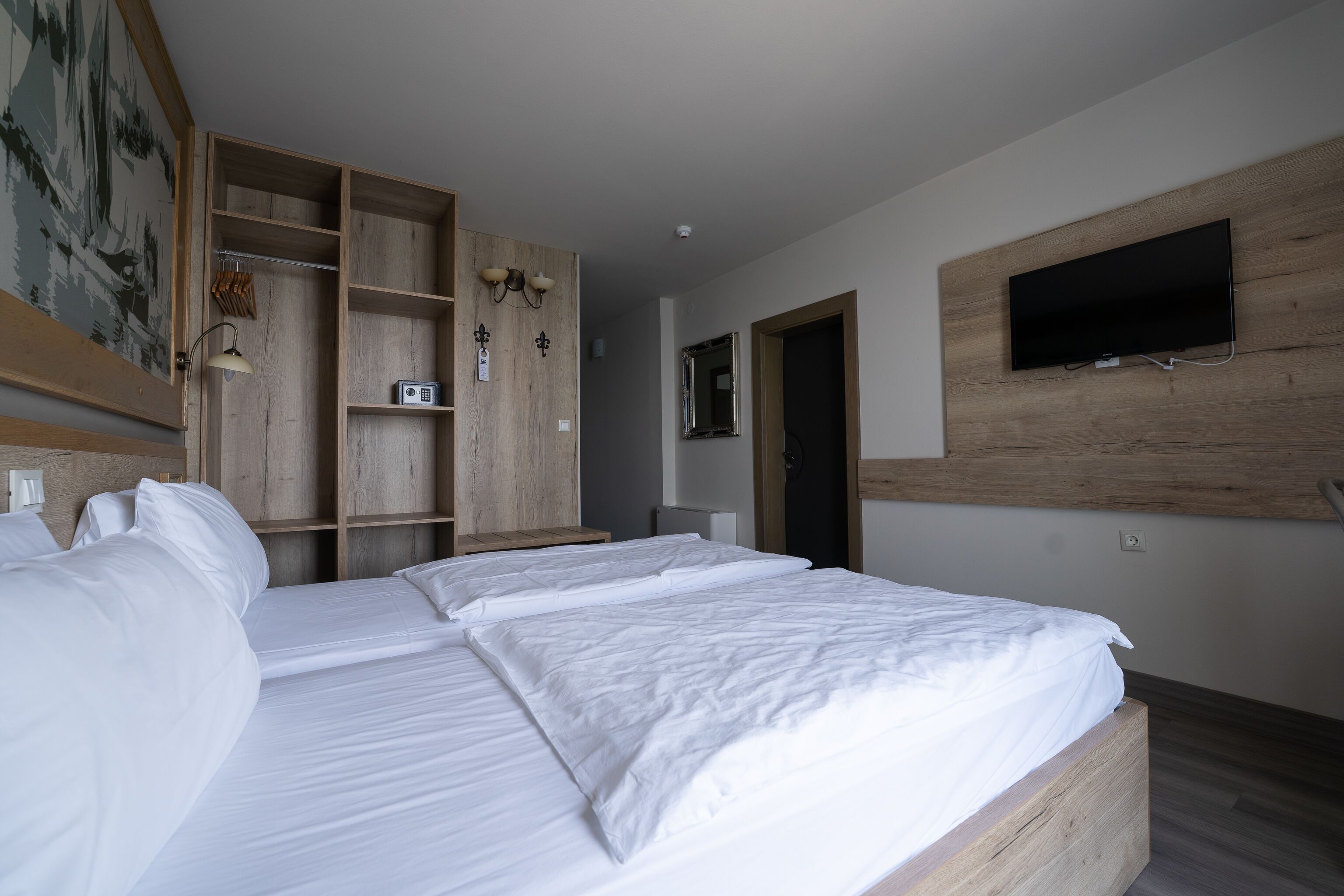 Ein Hotelzimmer mit einem großen Bett, einem an der Wand befestigten Fernseher und einem Holzschrank.